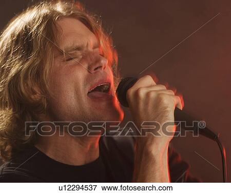 Man singing into microphone View Large Photo Image Stock Photo - Man singing into microphone. Fotosearch