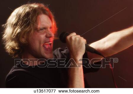 Man singing into microphone View Large Photo Image Stock Photo - Man singing into microphone. Fotosearch