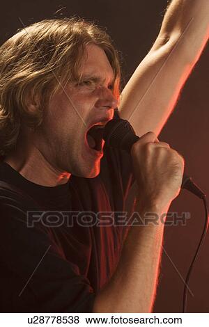 Man singing into microphone View Large Photo Image Stock Photo - Man singing into microphone. Fotosearch
