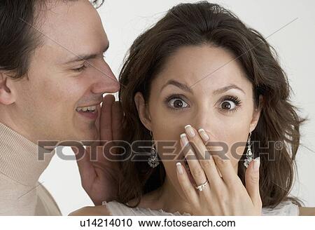Stock Image - Man telling woman a surprising secret. Fotosearch