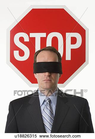 Stock Photography - Man wearing blindfold at stop sign. Fotosearch