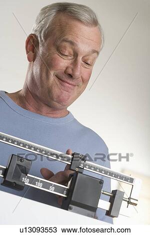 Stock Image - Man weighing himself. Fotosearch