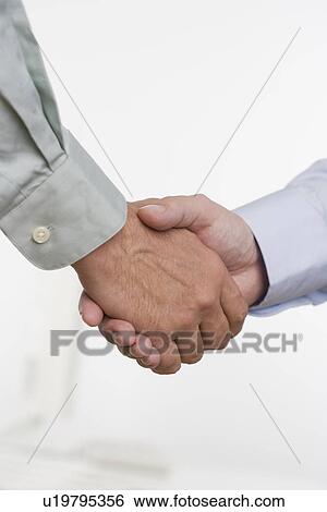 Stock Photograph - Men in shirtsleeves shaking hands. Fotosearch