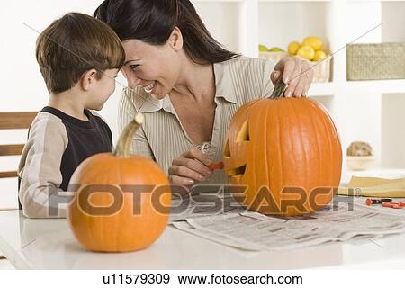 Stock Photo - Mother and son carving pumpkin. Fotosearch