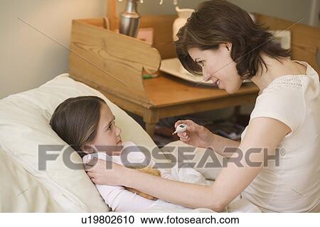 Mother checking young daughter’s temperature with thermometer View Large Photo Image Stock Image - Mother checking young daughter’s temperature with thermometer. Fotosearch