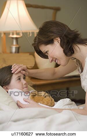 Stock Photo - Mother checking young daughter’s temperature. Fotosearch