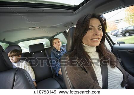Stock Photo - Mother driving with children in backseat. Fotosearch