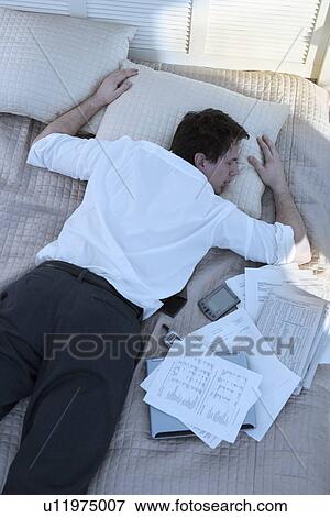 Overworked businessman sleeping with paperwork View Large Photo Image Stock Photo - Overworked businessman sleeping with paperwork. Fotosearch