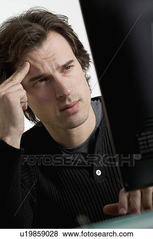 Stock Photo - Perplexed man at computer. Fotosearch