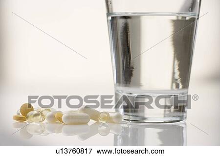Stock Photo - Pile of pills with water glass. Fotosearch