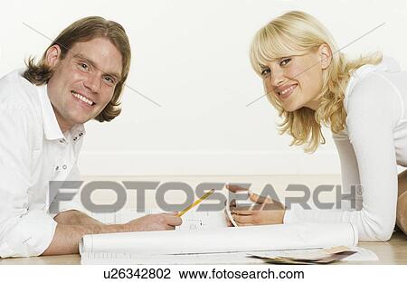 Stock Image - Portrait of couple with blueprints. Fotosearch