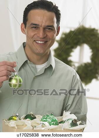 Stock Photo - Portrait of man holding Christmas ornament. Fotosearch