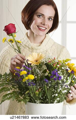 Stock Image - Portrait of woman arranging flowers. Fotosearch