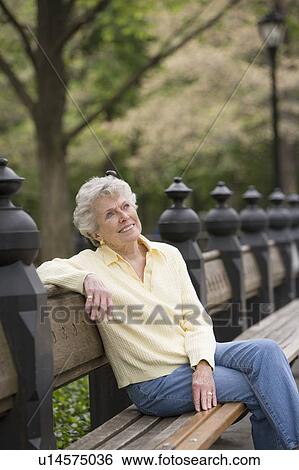Stock Photograph - Portrait of woman sitting on park bench. Fotosearch
