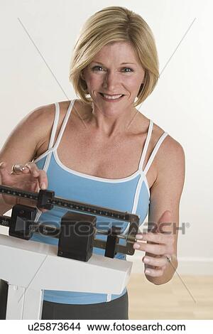 Picture - Portrait of woman weighing herself. Fotosearch