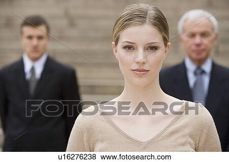 Stock Photo - Portrait of woman with businessmen in background. Fotosearch