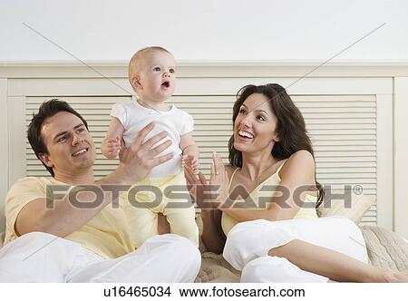 Picture - Proud couple lying down with infant. Fotosearch