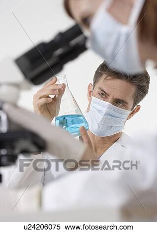 Scientists with microscope and blue liquid View Large Photo Image Stock Photography - Scientists with microscope and blue liquid. Fotosearch