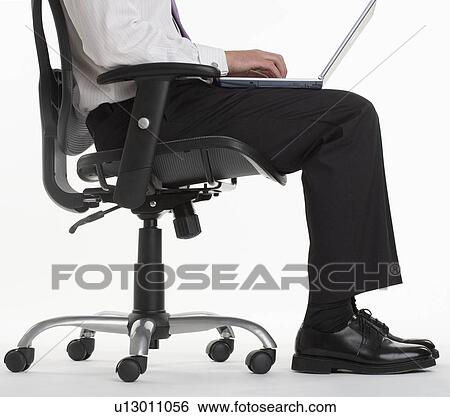 Seated businessman using laptop computer View Large Photo Image Stock Photograph - Seated businessman using laptop computer. Fotosearch