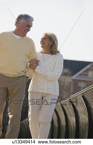 Picture - Senior couple walking arm in arm outdoors. Fotosearch