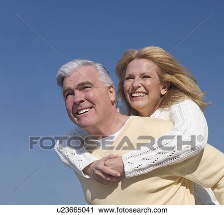 Senior man giving senior woman piggy back ride outdoors View Large Photo Image Stock Image - Senior man giving senior woman piggy back ride outdoors. Fotosearch
