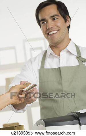 Stock Photography - Shopkeeper taking credit card. Fotosearch