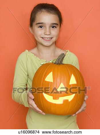Picture - Smiling girl holding a jack o lantern. Fotosearch