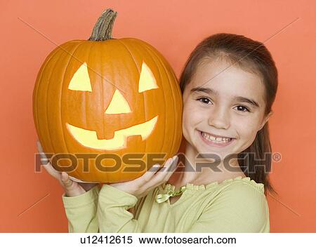 Stock Photography - Smiling girl holding a jack o lantern. Fotosearch