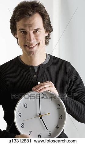 Smiling man holding clock View Large Photo Image Stock Image - Smiling man holding clock. Fotosearch