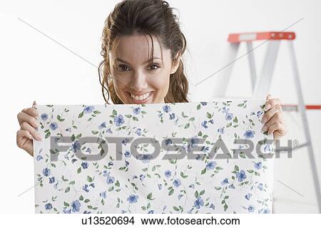 Smiling woman holding piece of wallpaper View Large Photo Image Picture - Smiling woman holding piece of wallpaper. Fotosearch