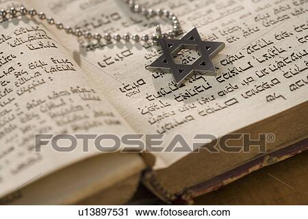 Stock Image - Star of David necklace on book with Hebrew text. Fotosearch