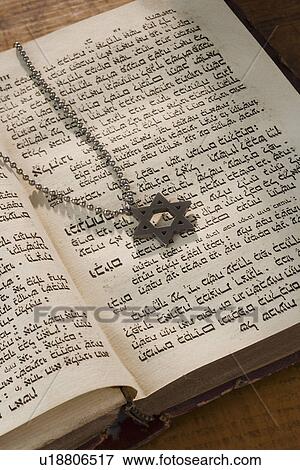 Stock Photo - Star of David necklace on book with Hebrew text. Fotosearch