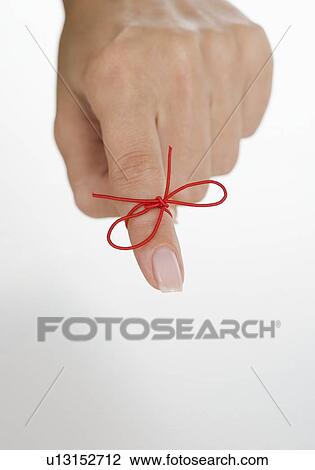 Stock Image - String tied around woman's finger. Fotosearch