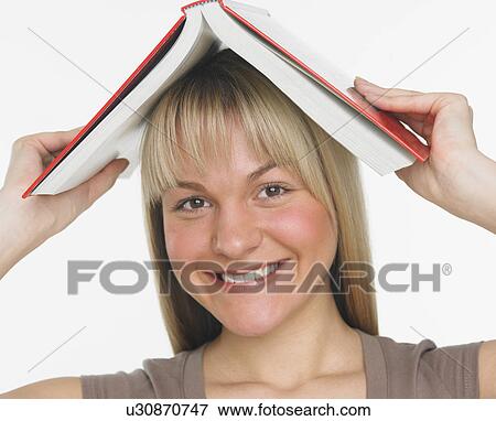 Stock Photo - Studio shot of woman holding a book over her head. Fotosearch