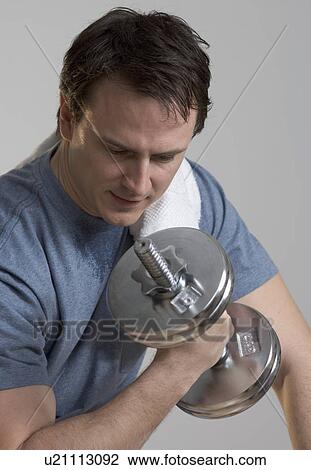 Stock Image - Sweating man lifting weights. Fotosearch