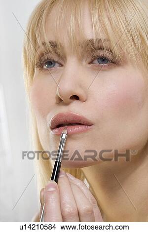Picture - Woman applying lipstick with brush. Fotosearch
