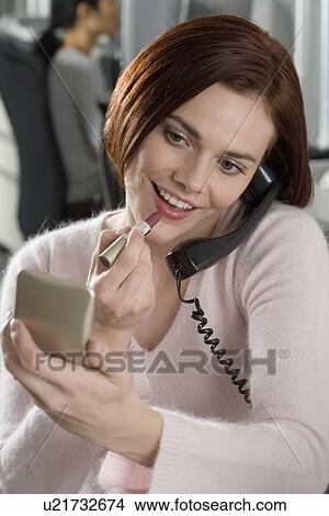 Picture - Woman at work applying lipstick. Fotosearch