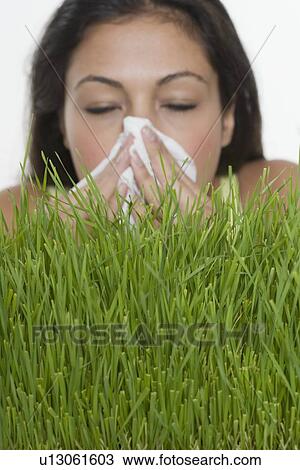 Stock Image - Woman blowing nose with grass. Fotosearch