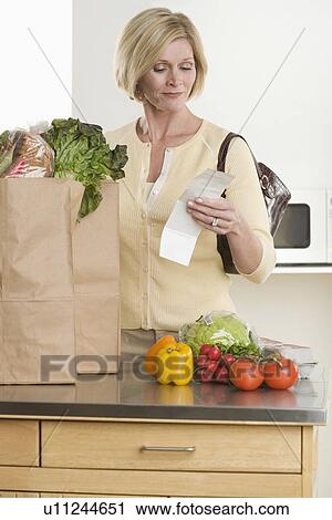 Stock Image - Woman checking grocery receipt. Fotosearch
