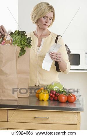 Stock Photography - Woman checking grocery receipt. Fotosearch