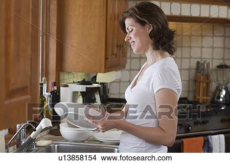 Picture - Woman drying dish at kitchen sink. Fotosearch
