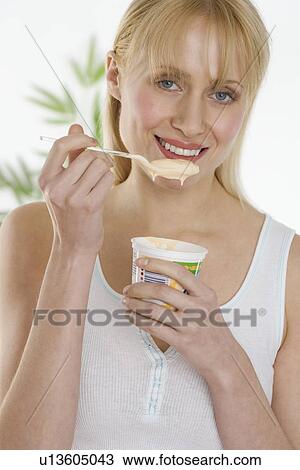 Stock Image - Woman eating cup of yogurt. Fotosearch