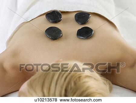 Stock Photo - Woman face down with stones on back. Fotosearch
