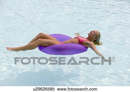 Woman floating in a swimming pool View Large Photo Image Stock Photography - Woman floating in a swimming pool. Fotosearch
