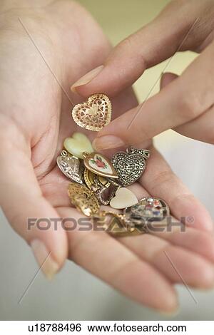Stock Photograph - Woman holding a handful of hearts-shaped vitamins. Fotosearch