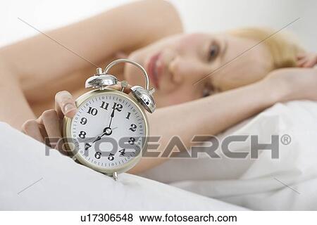 Stock Photo - Woman holding alarm clock. Fotosearch