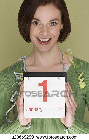 Stock Photo - Woman holding calendar on first day of the year. Fotosearch