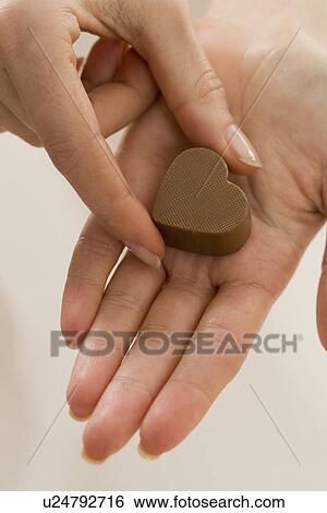 Stock Photograph - Woman holding chocolate candy. Fotosearch