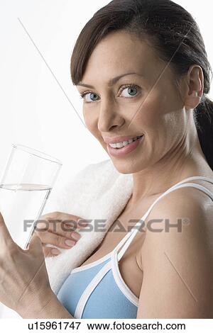 Woman holding glass of water after workout View Large Photo Image Stock Photo - Woman holding glass of water after workout. Fotosearch