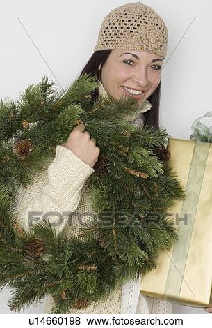 Stock Photo - Woman holding holiday wreath and present. Fotosearch